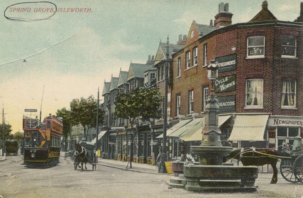 Historic postcard of Pears Fountain at Spring Grove, with a tram, horses and a newspaper and confectionery shop
